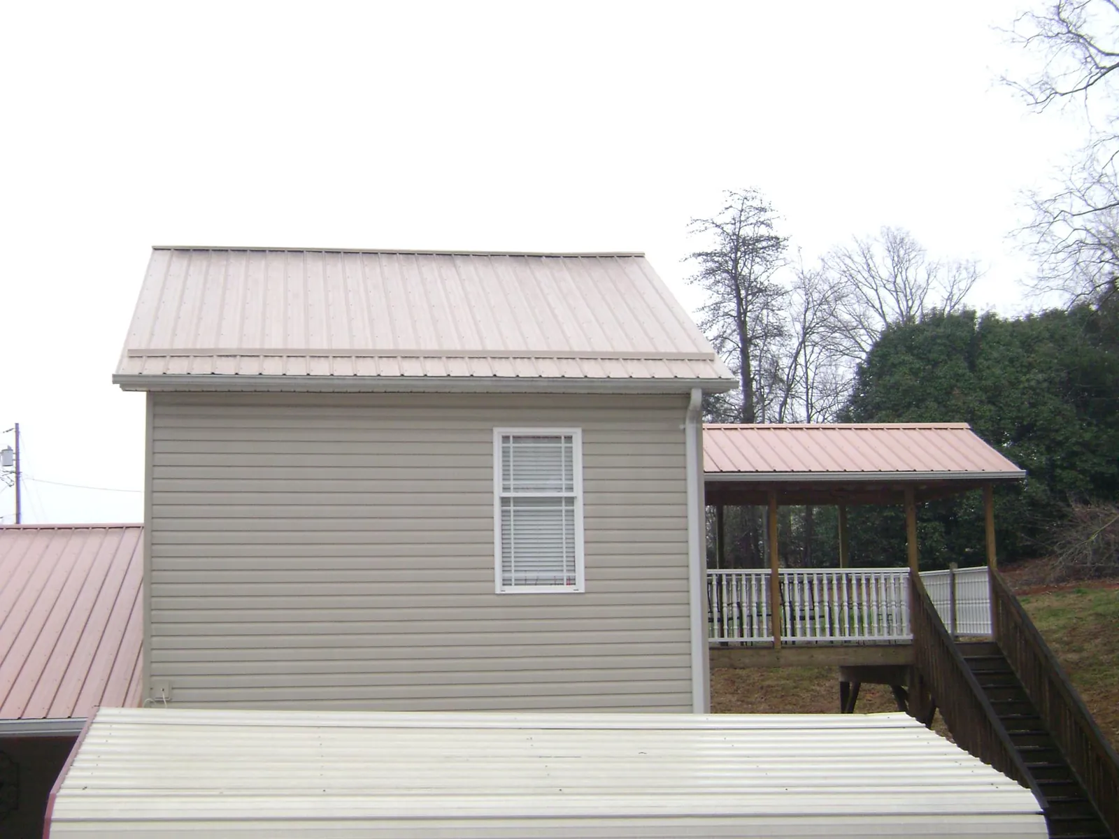 Tan metal roofs on a two story addition and attached porch in Goshen